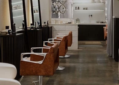 El interior de SESH By Jennifer Araujo en Caracas, VE muestra sillones elegantes marrones alineados.