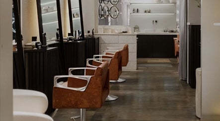 El interior de SESH By Jennifer Araujo en Caracas, VE muestra sillones elegantes marrones alineados.