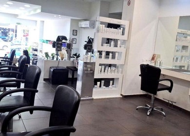 Εσωτερικό MISEL GROUP Κομμωτήρια Αιγάλεω, Αιγάλεω GR με κομψές καρέκλες και προϊόντα ομορφιάς.