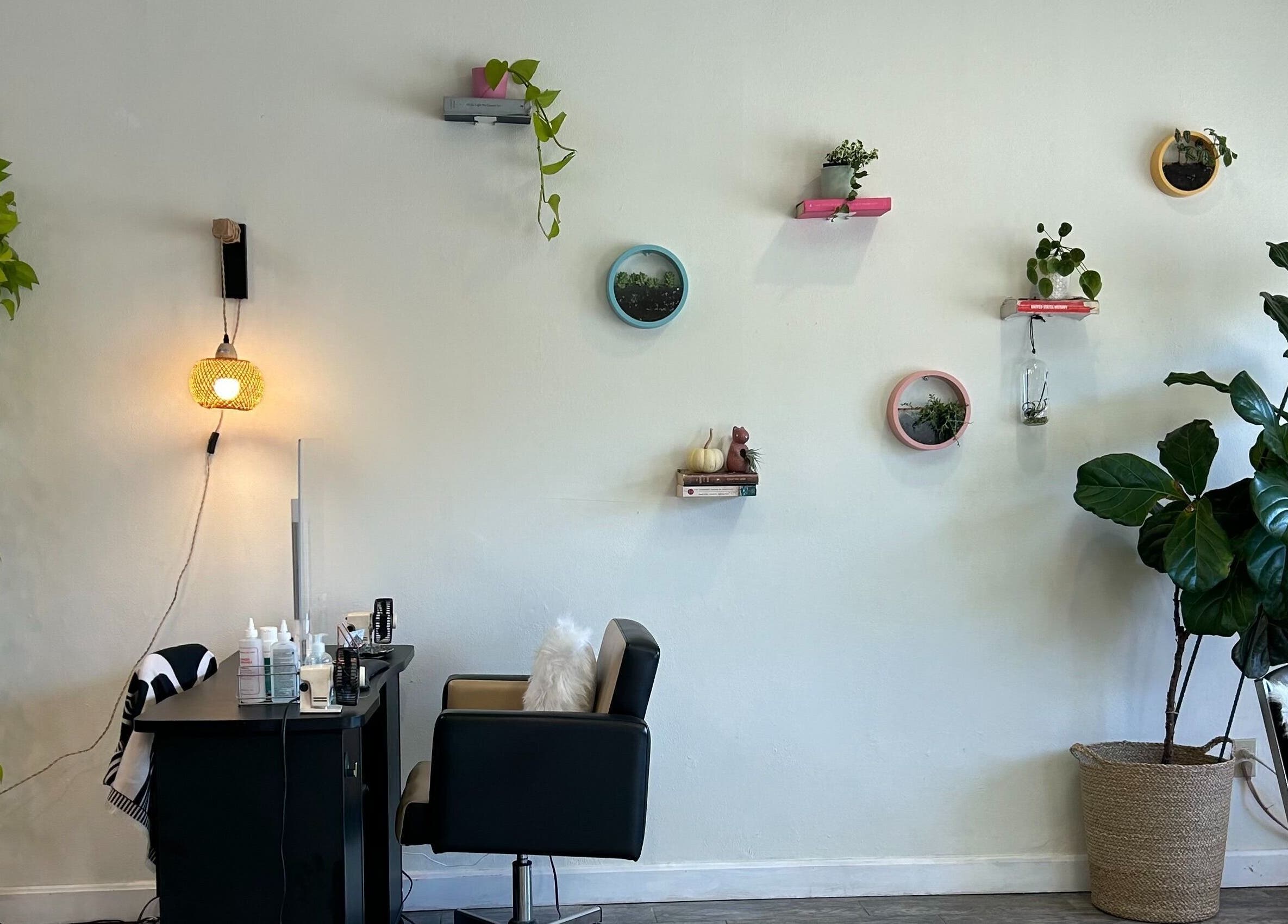 Nails Essential Spa in Cohasset, Massachusetts, US. Cozy corner with plants, wall decor, and salon chair for relaxation.