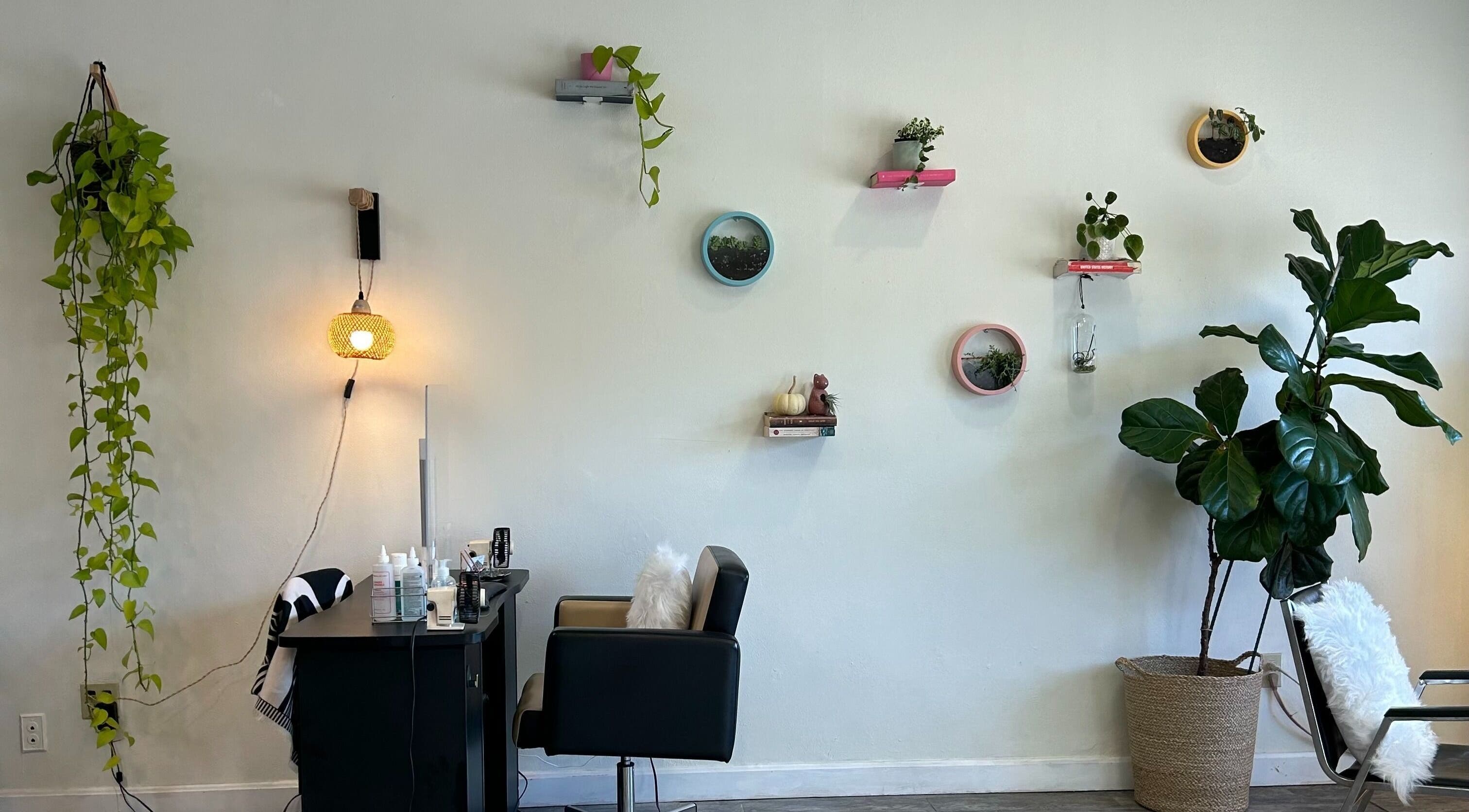 Nails Essential Spa in Cohasset, Massachusetts, US. Cozy corner with plants, wall decor, and salon chair for relaxation.