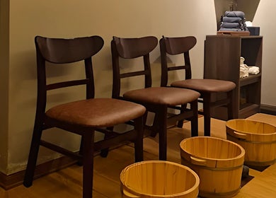 Wooden foot baths and chairs at Nón Spa, Đà Nẵng, Đà Nẵng, VN offer a relaxing wellness experience.
