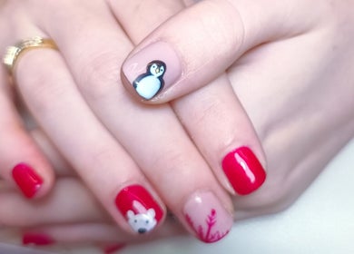 Penguin-themed nail art at The Rainbow Studio, Southampton, GB. Vibrant red polish with cute animal designs.