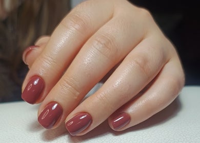 Elegant, maroon-manicured hand at The Rainbow Studio, Southampton, GB, showcasing glossy finish.