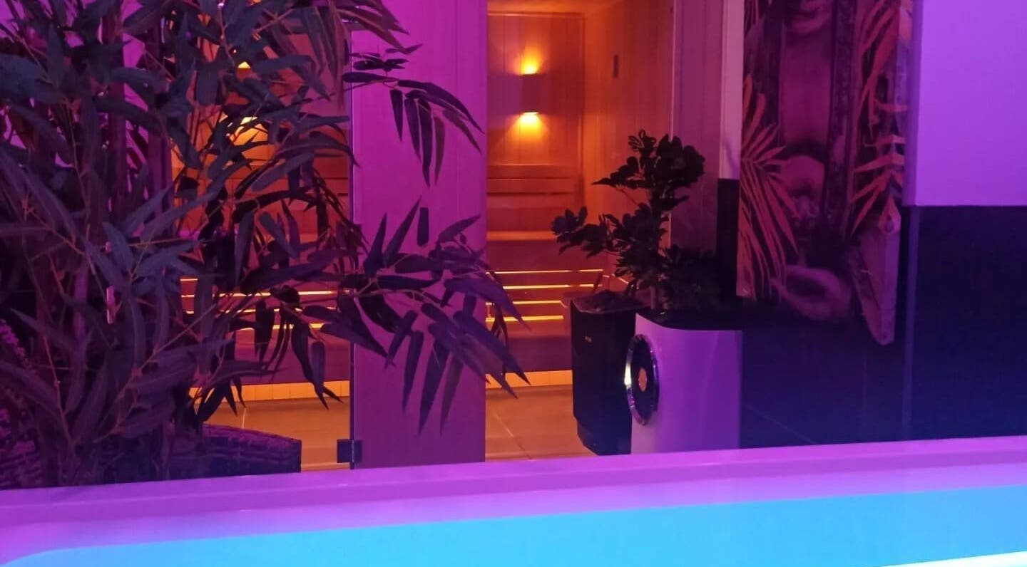 Sauna éclairé de WELLNESS KAFÉ à Thaon-les-vosges, Grand Est, FR, entouré de plantes luxuriantes.