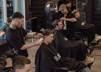 Men receiving haircuts at BAR x BAR Manly, Manly, New South Wales, AU. A modern, lively barbershop atmosphere.