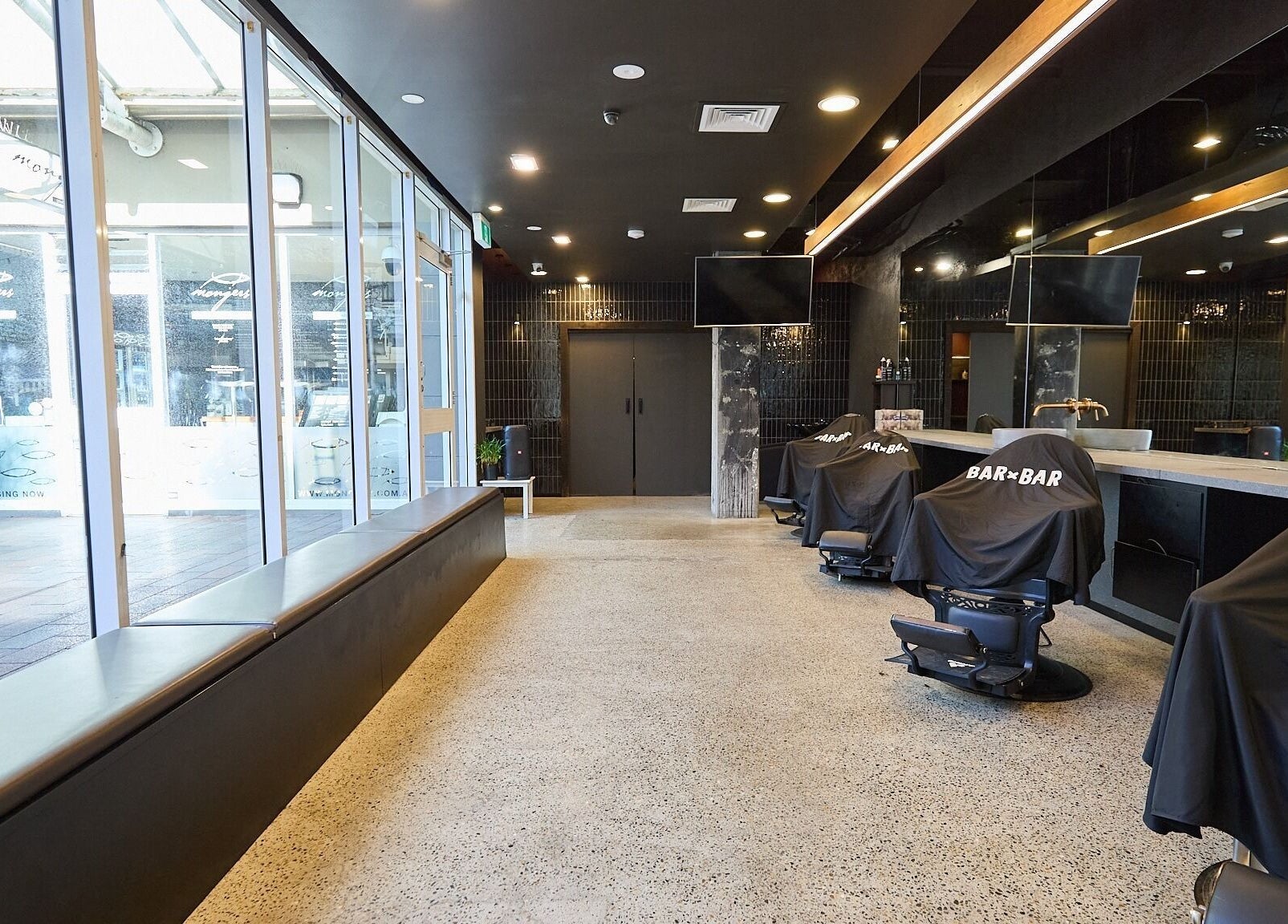 Modern interior at BAR x BAR Manly in Manly, New South Wales, AU, showcasing stylish barber chairs and large windows.