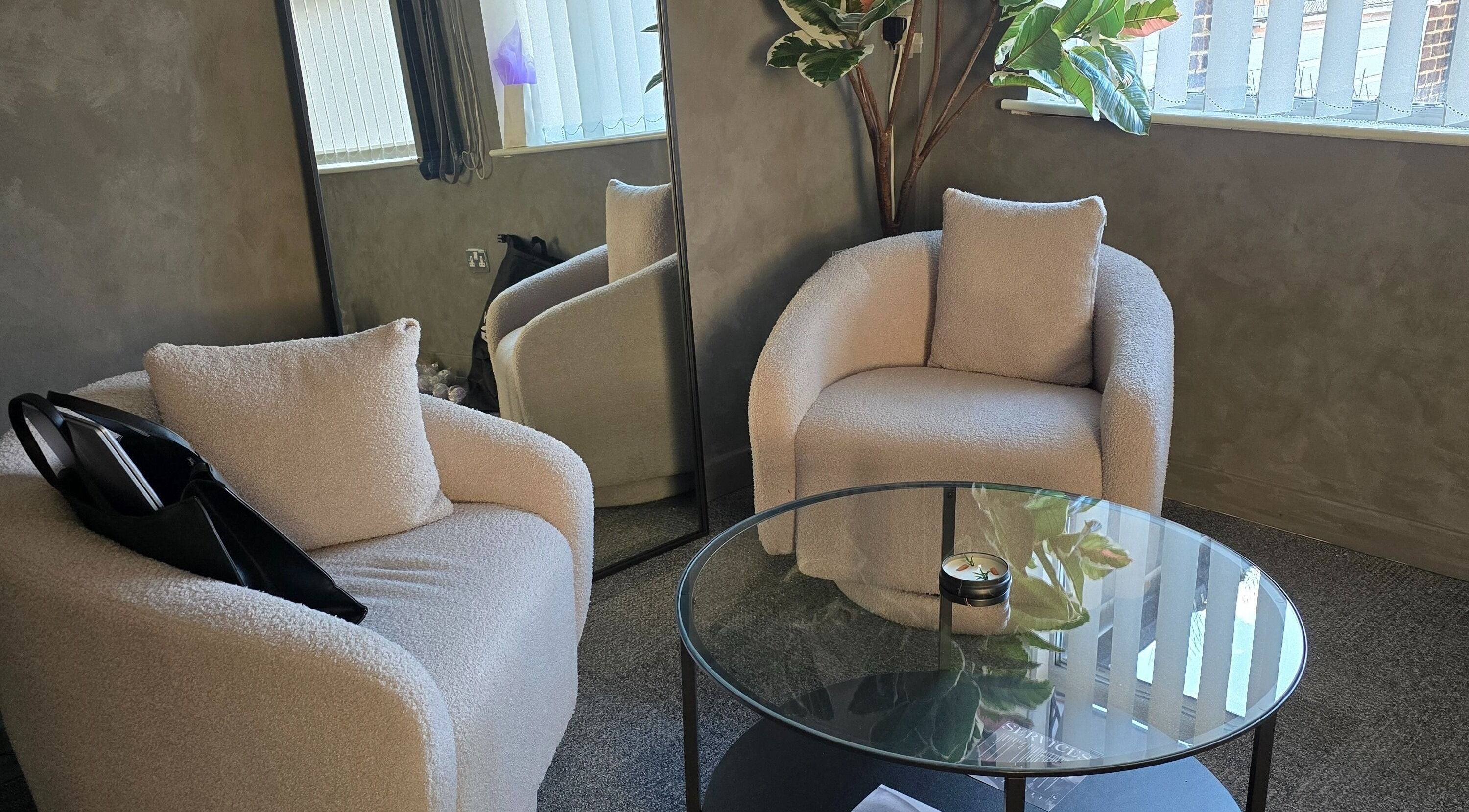 Relaxing seating area at Luna Body Therapy, Potters Bar, England, featuring plush chairs and a glass table.