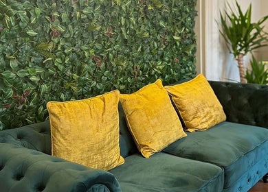 Green velvet sofa with yellow pillows at Chapter1 Salon, Cheltenham, England, GB offering a lush, relaxing vibe.