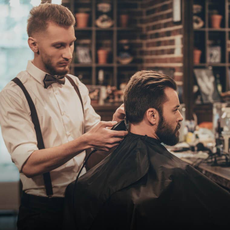 Barber styling a client's hair in a contemporary barbershop, highlighting barbering services on Fresha.