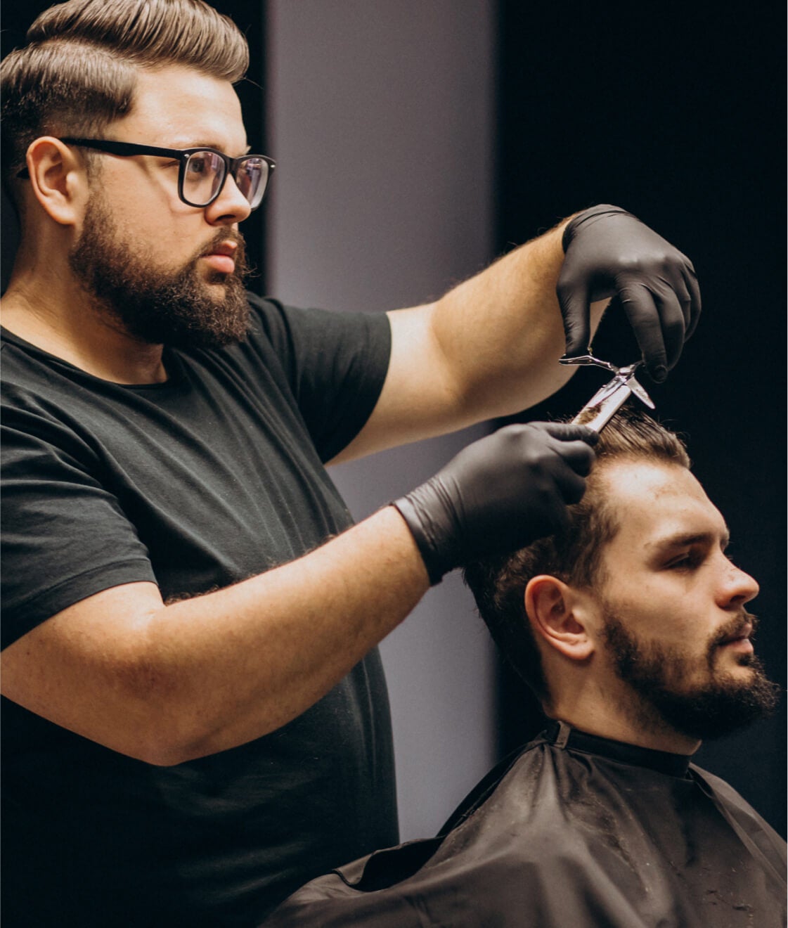 Ein Barbier schneidet den Bart eines Kunden in einem klassischen Barbiergeschäft.