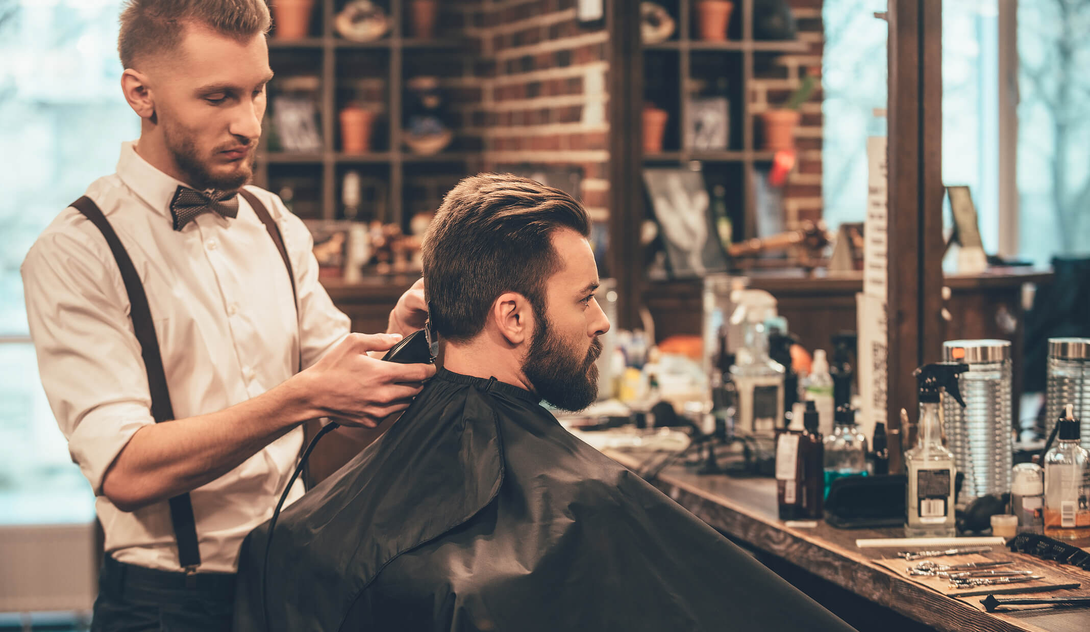 Ein Friseur stylt das Haar eines Kunden in einem modernen Friseursalon und hebt die Friseurdienstleistungen auf Fresha hervor.