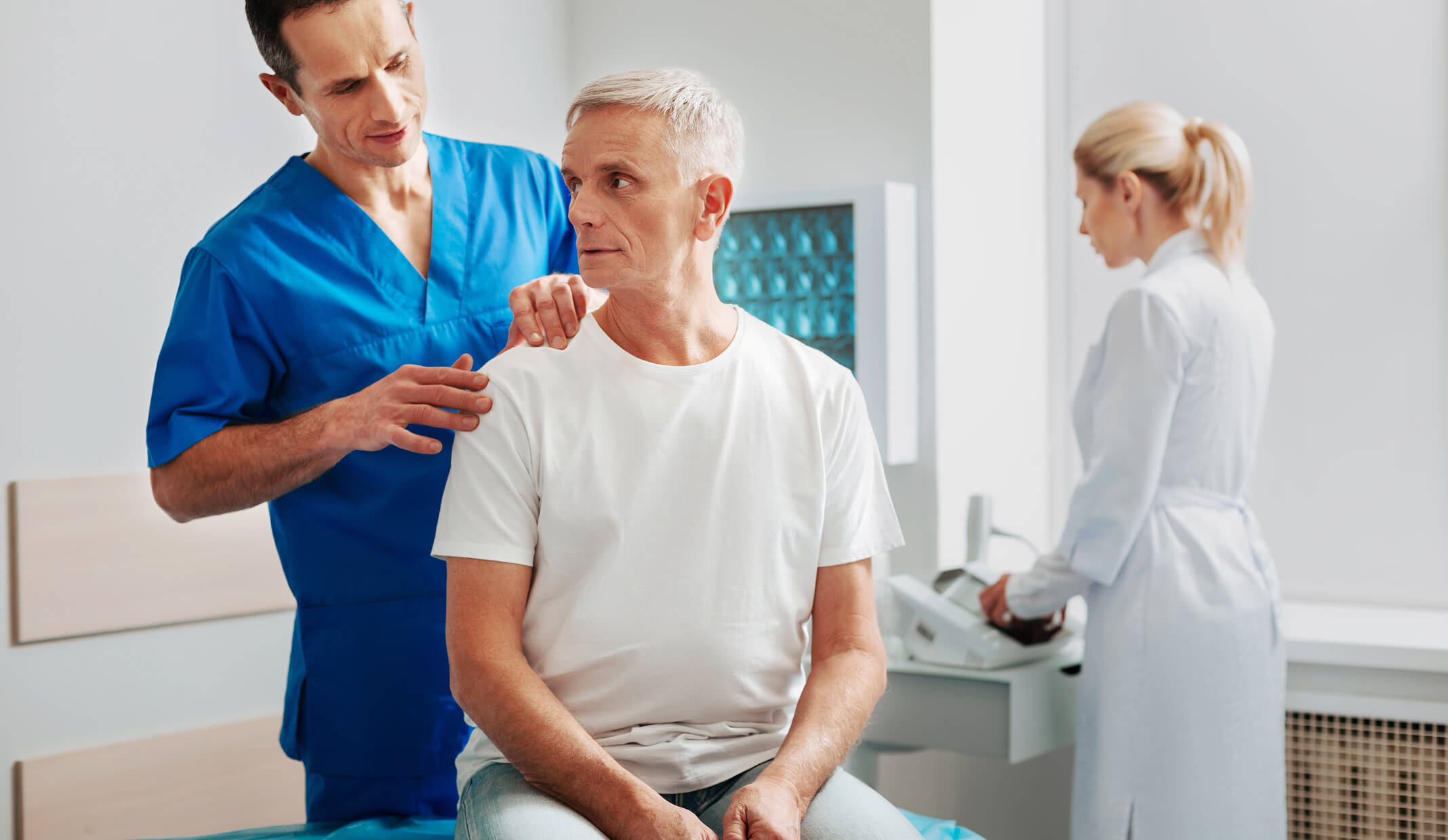 Eine lächelnde Sprechstundenhilfe an der Rezeption einer hellen, modernen Arztpraxis spricht mit einem Patienten.