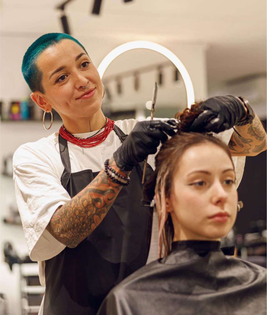 Hair stylist cutting and styling a woman's hair in a modern salon.