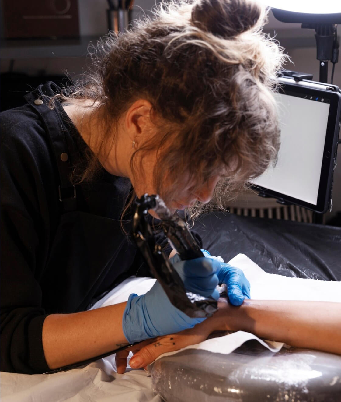 Tattoo artist creating a detailed tattoo on a client's arm.