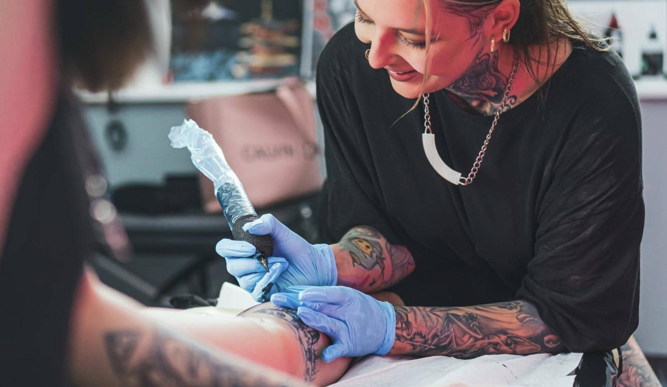 Tattoo artist creating a detailed design on a client's arm in a studio, illustrating tattoo and piercing services on Fresha.