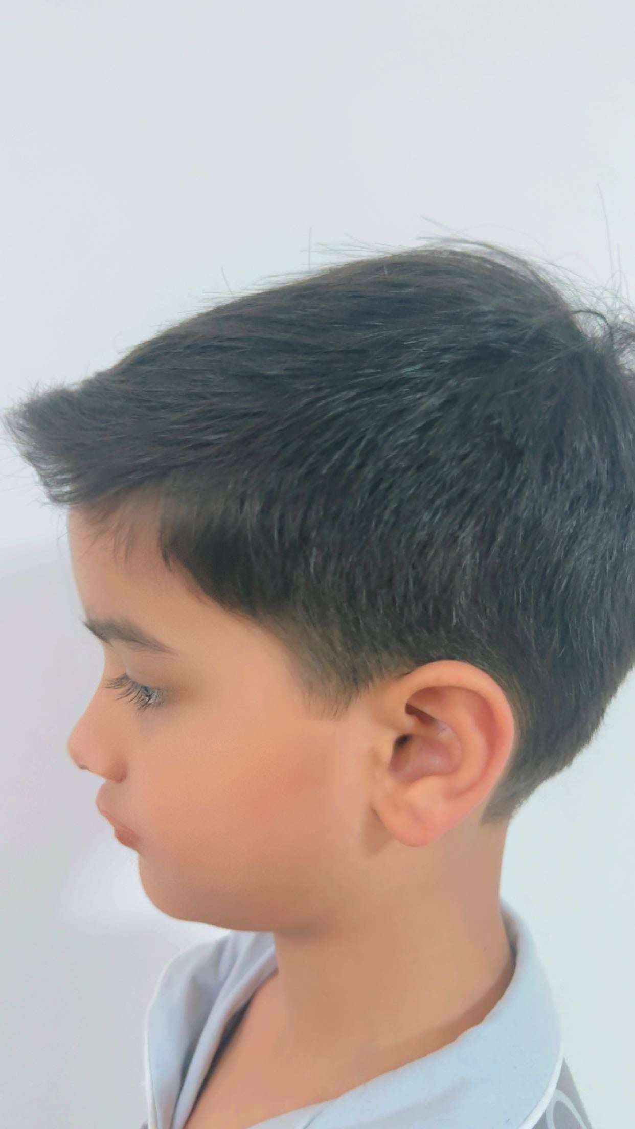 A young boy with a freshly styled haircut, showcasing a neat and tidy look by Peekaboo Kids Salon in Muscat, Oman.