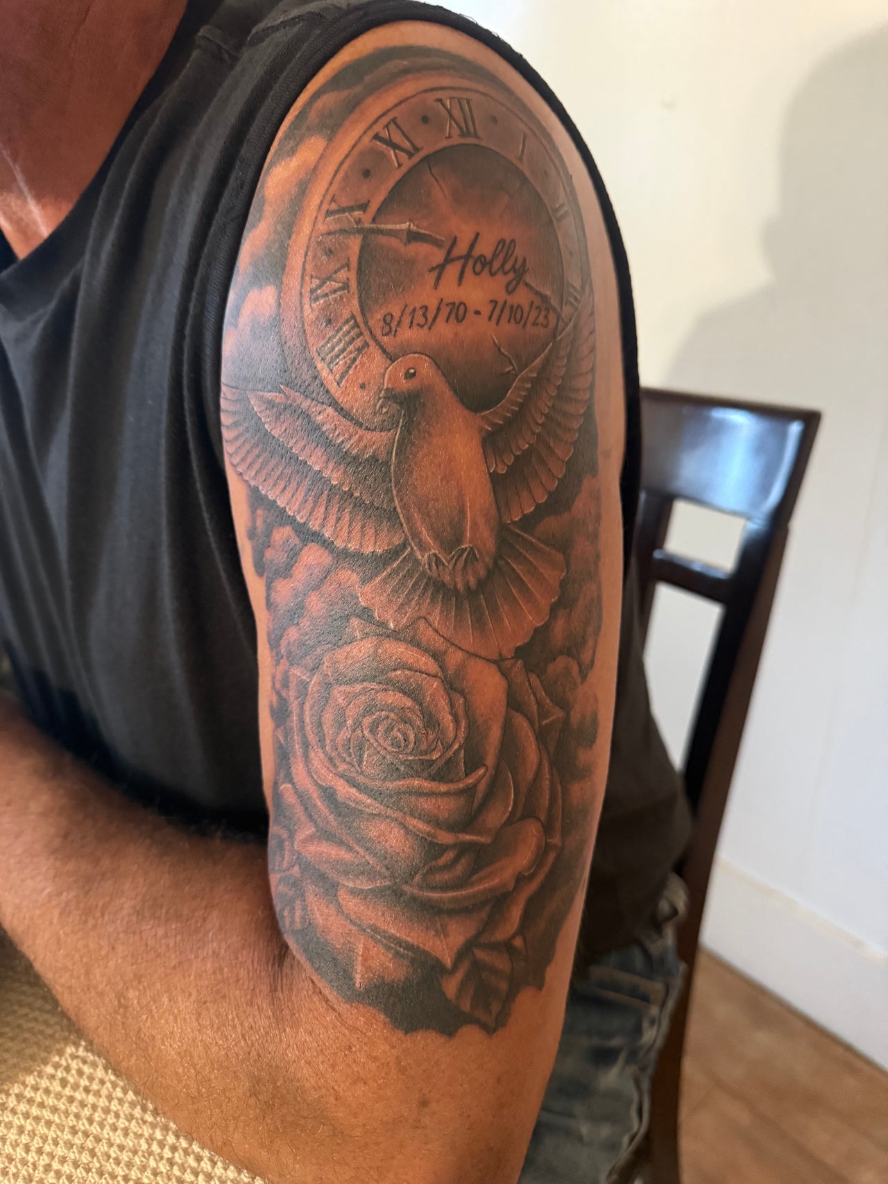 A detailed black and grey tattoo sleeve featuring a clock, dove, and roses by Cryptic Tattoos in Scottsbluff, Nebraska, US